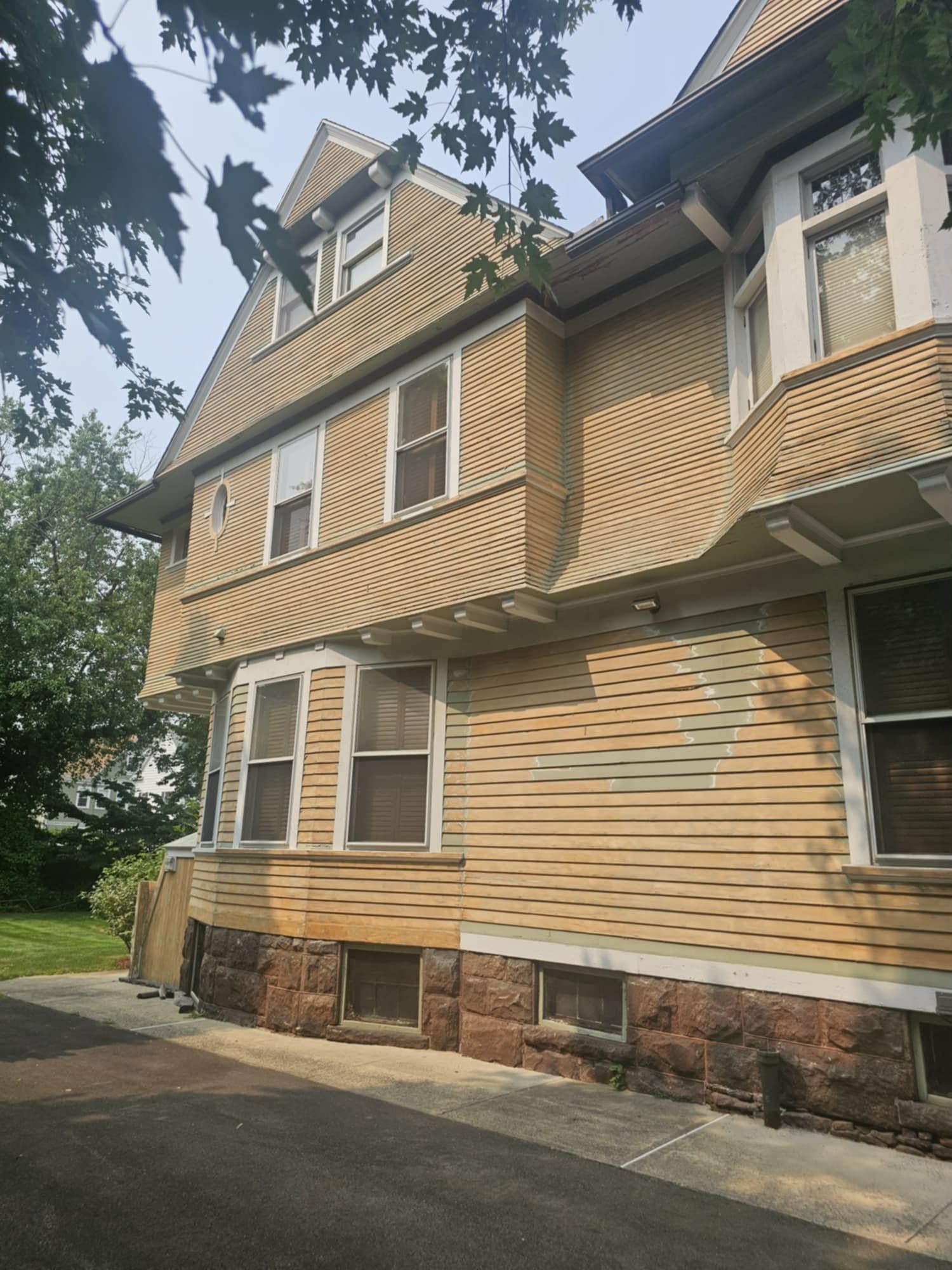 Before: side of a three-story house with faded yellow siding
