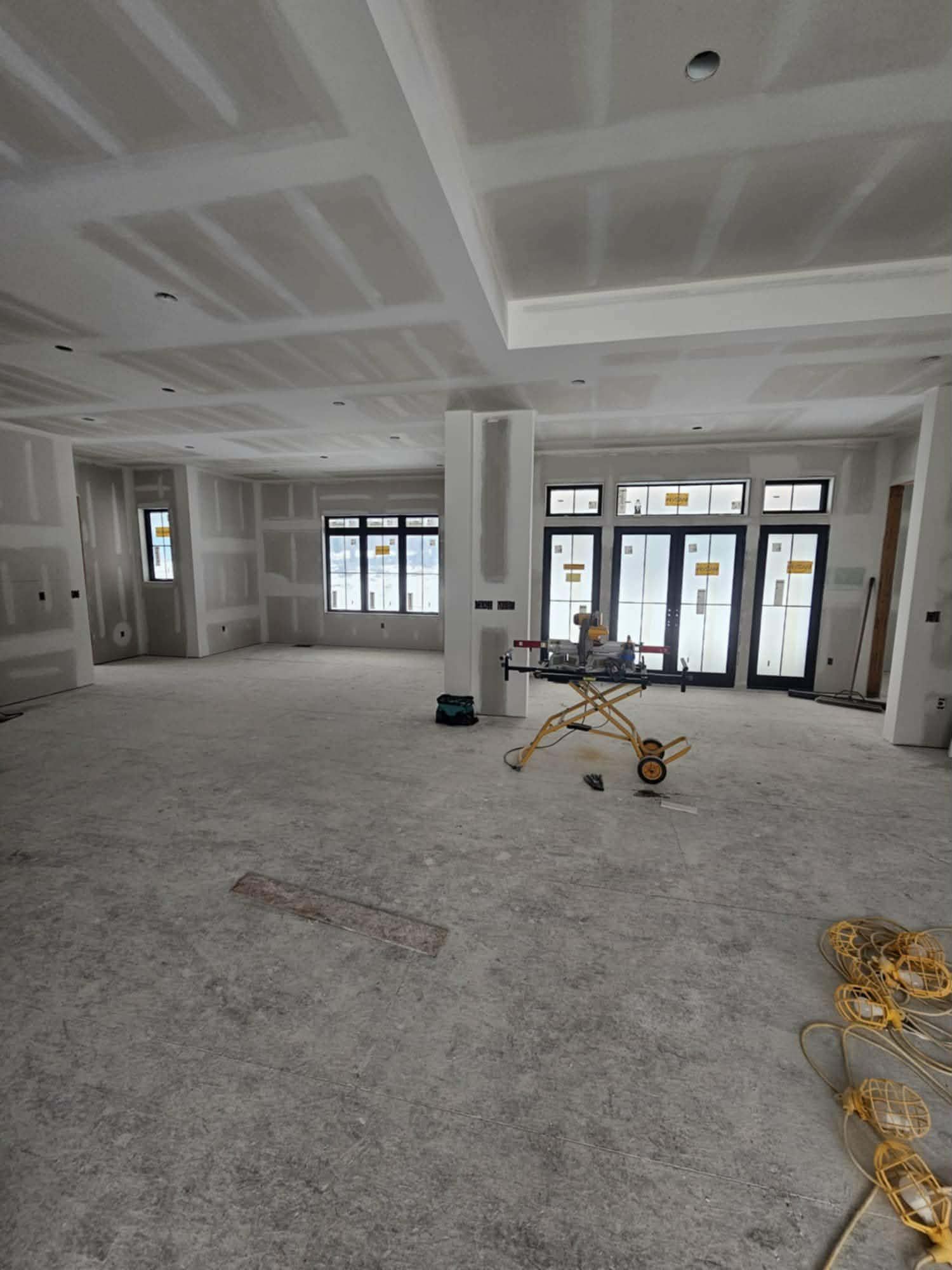 Open-plan room with new drywall and a coffered ceiling, ready for finishing